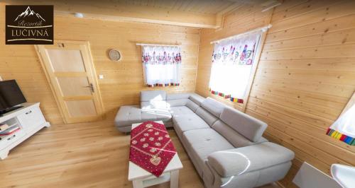 a living room with a white couch in a wooden room at Rezortík Lučivná pre rodiny s deťmi, 300m od vleku, Vysoké Tatry in Lučivná