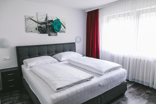 a bedroom with a bed with white sheets and a window at Apartments Margarethenbad in Rangersdorf