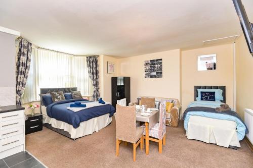 1 dormitorio con 2 camas, mesa y sillas en The Elm Wood Apartments, en Huddersfield