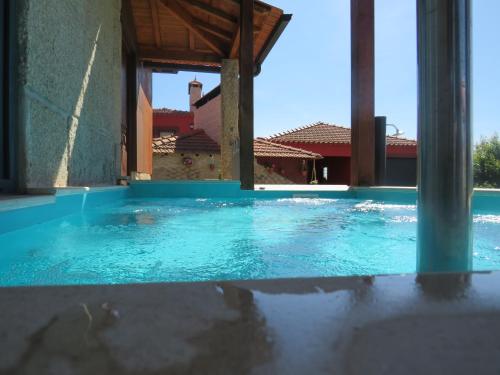 a swimming pool with blue water in a building at Solar dos Alperces - Serra da Estrela - Turismo de Aldeia in Travancinha