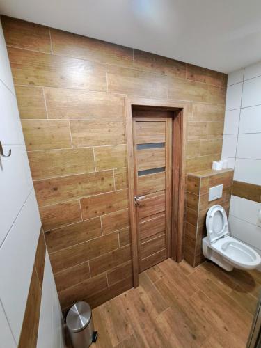a bathroom with a toilet and a wooden wall at Horský Dům Horalka in Železná Ruda