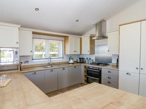 a large kitchen with white cabinets and a sink at Ystwyth 36 in Borth