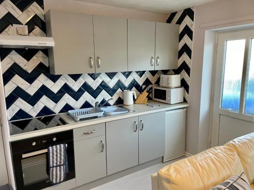uma cozinha com armários brancos e uma parede xadrez em Apartment 49, Ground floor, 2 Bedrooms with parking em Brean