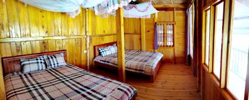 two beds in a room with wooden walls and windows at Madame View Homestay in Sa Pa