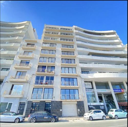 a large white building with cars parked in front of it at F1 - Modern two bedrooms Flat sea View, St Julians in St Julian's