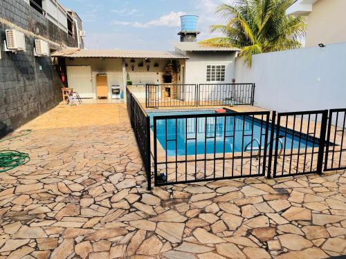 a swimming pool with a fence in front of a house at Hotel Solaris in Três Lagoas