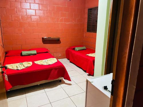 Duas camas num pequeno quarto com paredes vermelhas em Hotel Solaris em Três Lagoas