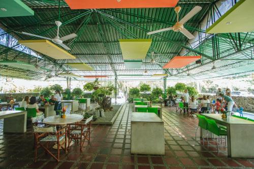 a restaurant with tables and chairs and people sitting at tables at Makenke Hostel By Los Colores Ecoparque in Doradal