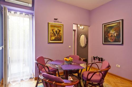 uma sala de jantar com paredes roxas e uma mesa e cadeiras em Marina Apartment em Belgrado