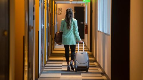 a woman walking down a hallway pulling a suitcase at ibis styles Lima San Isidro in Lima