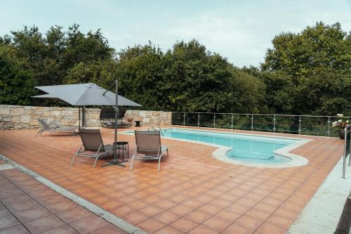a pool with a table and chairs and an umbrella at Casa Vacacional en Vilagarcía de Arousa in Vilagarcia de Arousa
