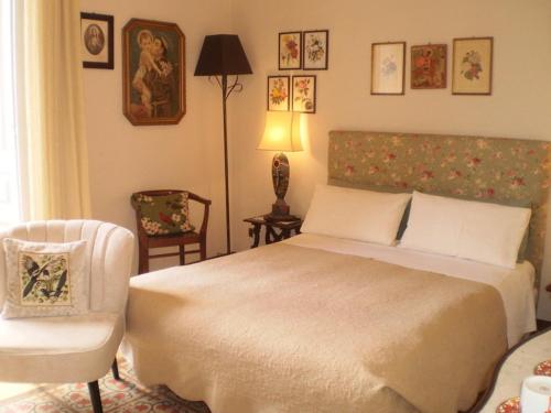 a bedroom with a bed, chair, lamp and a painting on the wall at Crociferi B&B in Catania