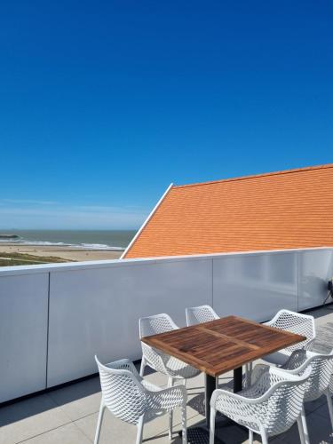 a wooden table and chairs on a balcony with the ocean at Penthouse Windkracht 10 aan het strand van Cadzand in Cadzand