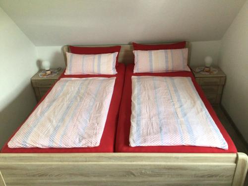 una camera con 2 letti con lenzuola e cuscini rossi di Nordseekrabbe Bollmann a Carolinensiel