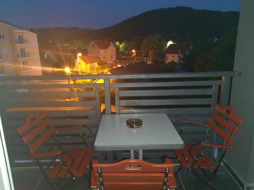 una mesa y sillas en un balcón por la noche en Stan na dan Niksic, en Nikšić