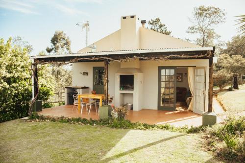 a small white house with a wooden deck at Fernhill Guest Farm in Knysna