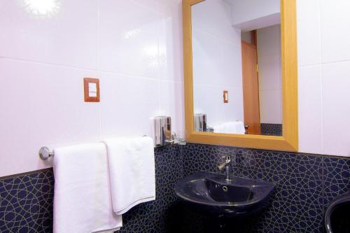 a bathroom with a sink and a mirror and towels at Apartahotel KIRI para empresas y familias que viajan en grupo cerca del Aeropuerto Juliaca Perú in Juliaca