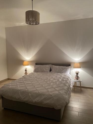 a bedroom with a large bed with two lamps at L’orthographe in Villers-Cotterêts