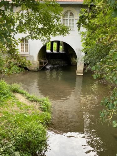 a bridge over a river in front of a building at LE GAI LO GITE in Villers-Pol