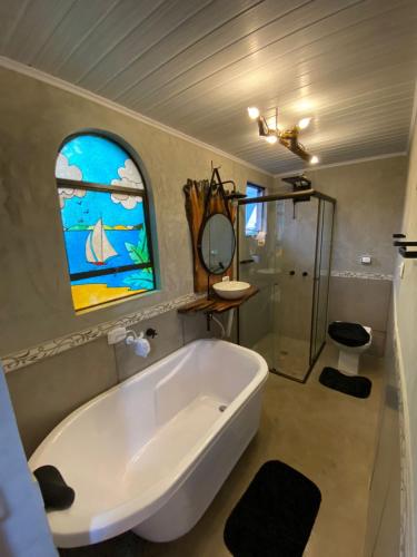 a bathroom with a tub and a stained glass window at Queiroz Palace Hotel in Siqueira Campos