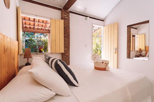 凱拉伊夫的住宿－Vila das Ondas Caraíva，卧室设有一张白色大床和两个窗户。