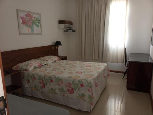 a bedroom with a bed with a floral bedspread at Solar da Praia in Vitória