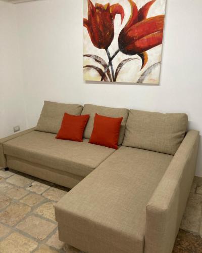 a couch with two red pillows sitting under a painting at Dimora Sofia in Polignano a Mare