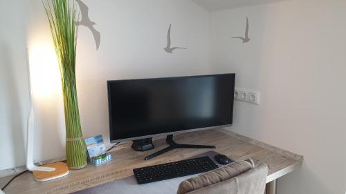 a computer monitor and keyboard on a desk with a plant at Urlaubsdomizil InselLust-Rügen in Sassnitz