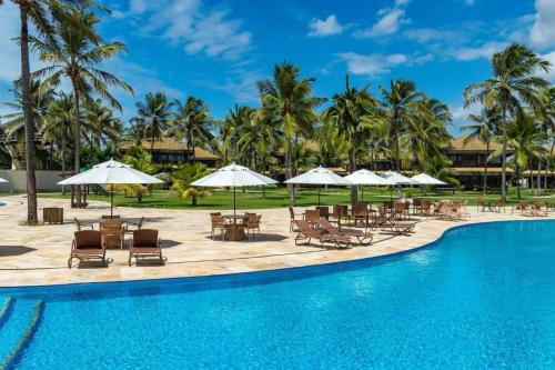 a pool at the resort with chairs and umbrellas at ECO FLECHEIRAS RESIDENCE in Trairi