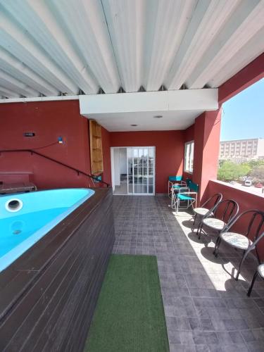 uma piscina num quarto com paredes vermelhas e cadeiras em Plaza em Termas de Rio Hondo