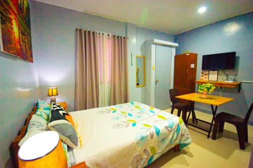 a bedroom with a bed and a table and a desk at Lovely Studio 1 Bedroom Apartment, Olongapo City Centre in Olongapo
