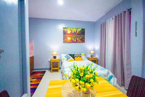 um quarto com uma cama e uma mesa com flores em Lovely Studio 1 Bedroom Apartment, Olongapo City Centre em Olongapo