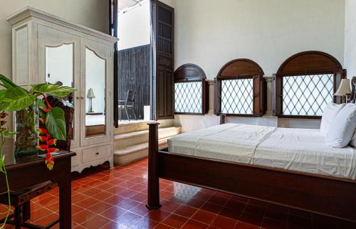 a bedroom with a bed and windows and a plant at VILLA MERIDA BOUTIQUE HOTEL - Adults Only in Mérida