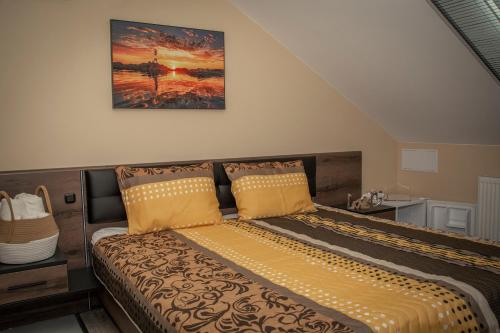 a bed in a bedroom with a painting on the wall at Oros House Apartmanház in Orosháza
