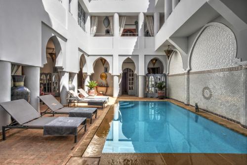 Riad Shemsi في مراكش: حمام سباحة داخلي مع كراسي صالة جلوس و مسبح.