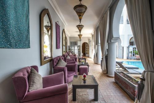 sala de estar con sillas moradas y piscina en Riad Shemsi en Marrakech
