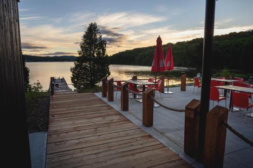 Station Touristique Duchesnay - Sepaq في Sainte-Catherine: رصيف خشبي مع طاولات وكراسي على البحيرة