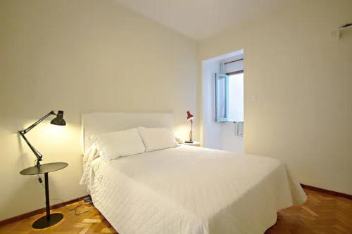 a bedroom with a white bed with a lamp and a window at Ipanema lindo apartamento, lugar tranquilo in Rio de Janeiro