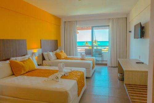 a hotel room with two beds and a view of the ocean at Enotel Porto de Galinhas All Inclusive in Porto De Galinhas
