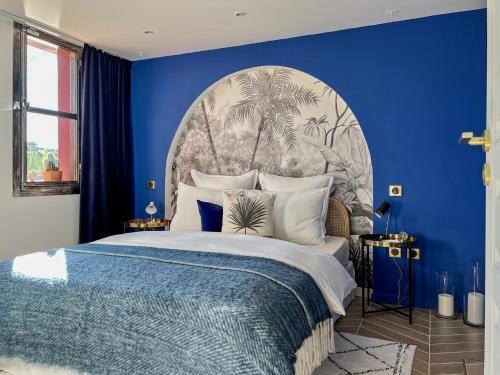 ein blaues Schlafzimmer mit einem großen Bett und einer blauen Wand in der Unterkunft Ness Cottage, le calme absolu à 15 minutes des plages in Le Beausset
