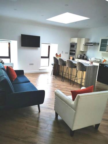 a living room with a couch and chairs and a kitchen at Elmwood House Luxury Seaview Accommodation in Donegal