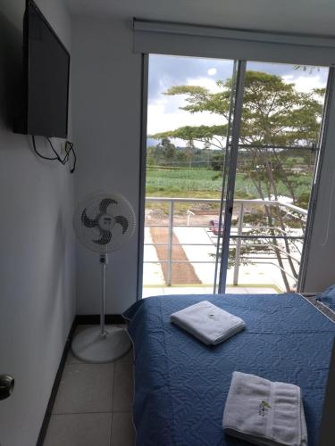 a bedroom with a bed and a window with a view at Apartamento y Piscina a 3' del Parque del Cafe in Montenegro