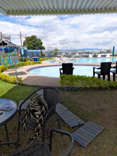 a bench and a table in front of a pool at Apartamento y Piscina Espectacular a 3' del Parque del Cafe in Montenegro