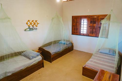 2 Betten in einem Zimmer mit Moskitonetzen in der Unterkunft Casa ampla c redes de descanso, Praia de Macapa PI in Luis Correia