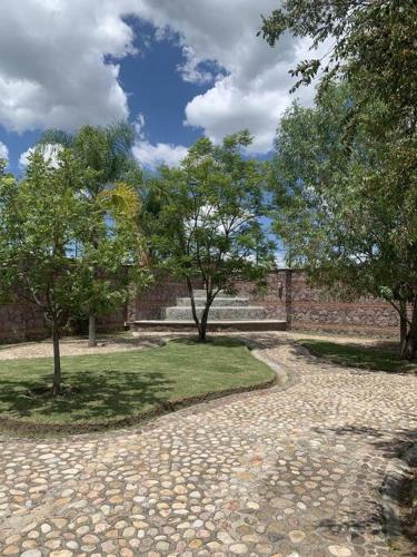 a stone path in a park with trees and a building at Villa Quinta Lomas casa completa con aéreas verdes in León