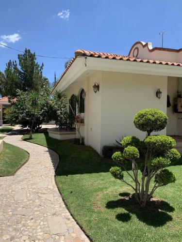 a white house with a walkway next to a yard at Villa Quinta Lomas casa completa con aéreas verdes in León