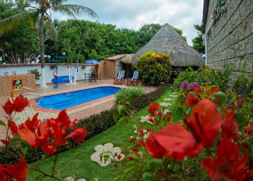 a resort with a swimming pool and a thatch roof at Portoazul Casa de Playa in Puerto Colombia