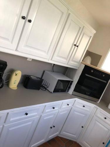 a white kitchen with white cabinets and a microwave at Gîte Malgré tout in Aydius