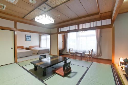 een woonkamer met een tafel en een slaapkamer bij Onsen Hotel Nakahara Bessou Nonsmoking, Earthquake retrofit in Kagoshima