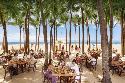 a group of people sitting at tables on the beach at Beach Park Resort - Suites in Aquiraz